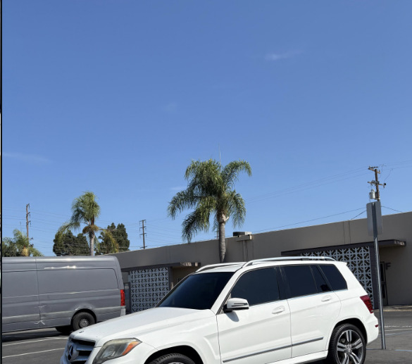 A white Mercedes SUV with tinted windows parked in the shop lot