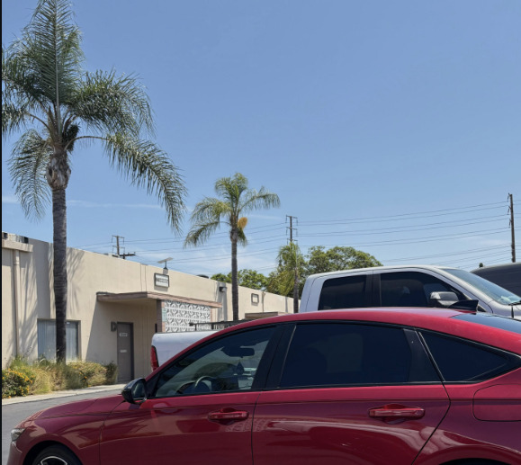 A red sedan with tinted windows parked in the shop lot